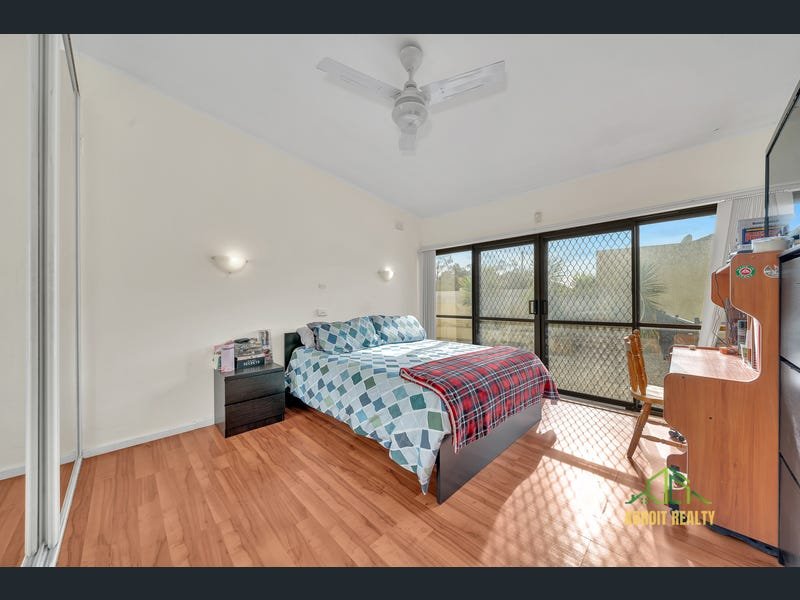 Modern bedroom featuring a double bed with geometric bedding, laminate wood flooring, and large sliding glass doors.