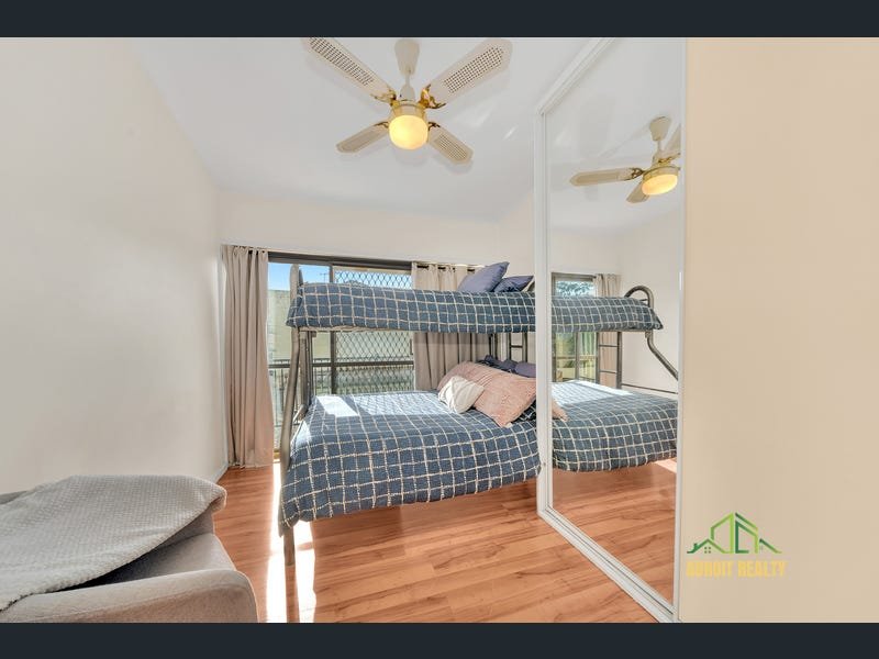 Modern bedroom featuring a metal bunk bed with blue checkered bedding, wood-look flooring, and a mirrored wardrobe.