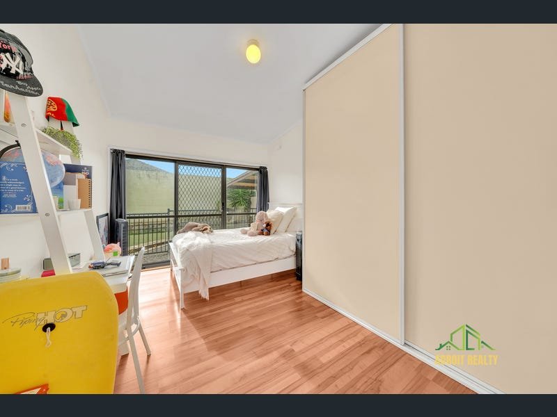 Modern child's bedroom with a white bed, wood-look flooring, large sliding glass doors, and a built-in wardrobe with cream sliding doors.