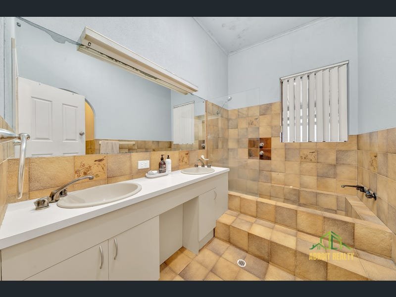 Spacious bathroom featuring a double vanity with white cabinetry and an integrated sunken bathtub with earthy-toned tiling.